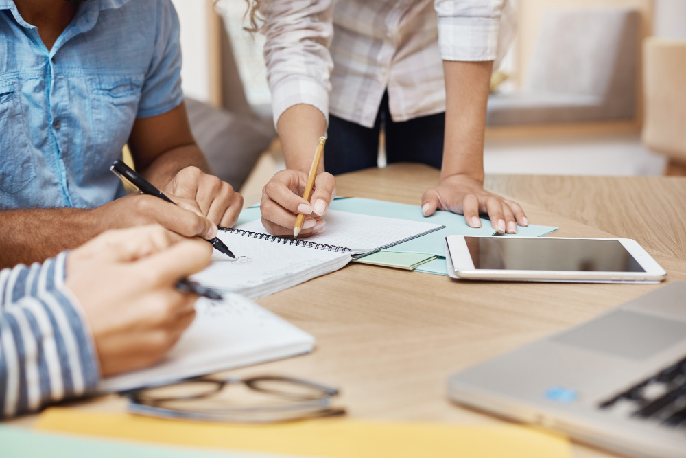 Aplicaciones del coaching y mentoring en RRHH: Método GROW y Conversaciones de desarrollo - detalle equipo trabajando nuevo proyecto espacio coworking escribiendo ideas mirando graficos tableta computadora portatil trabajo equipo concepto negocio